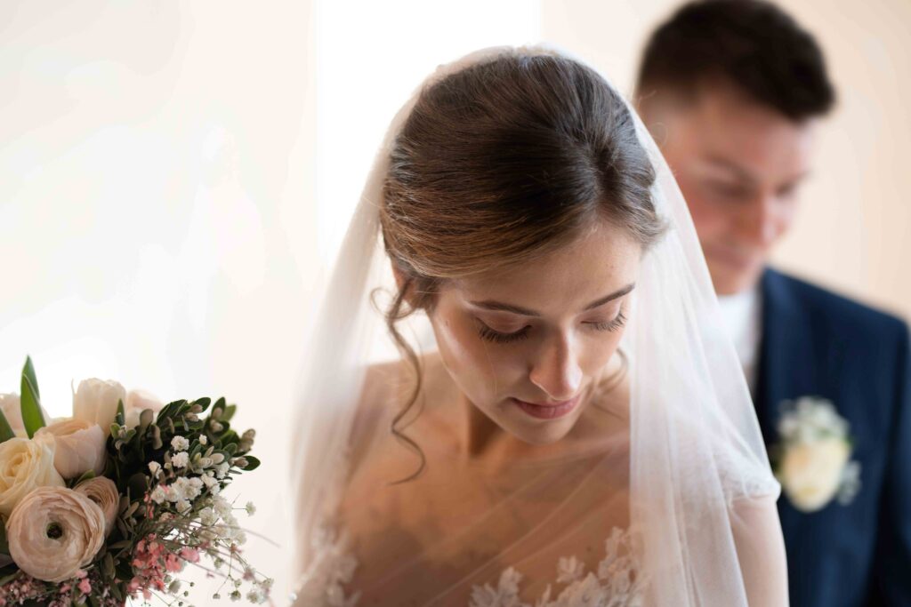La sposa con il bouquet e lo sposo sullo sfondo